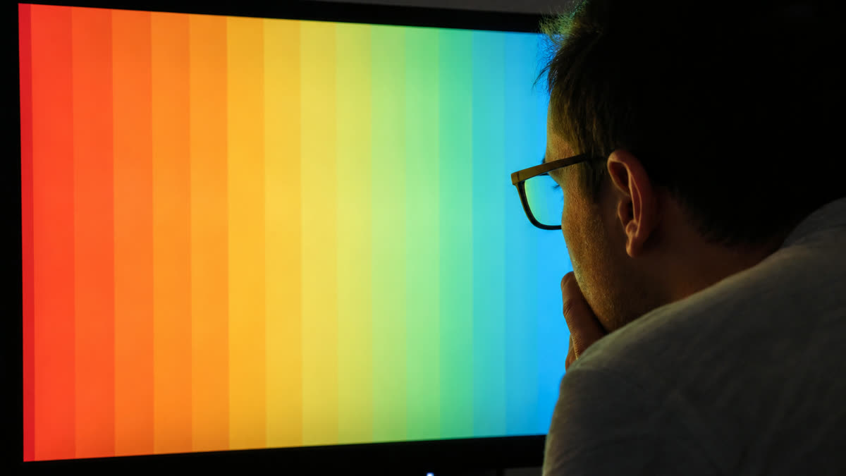 A monitor color gradient with obvious hard stripes instead of a smooth blend while someone inspects the panel.