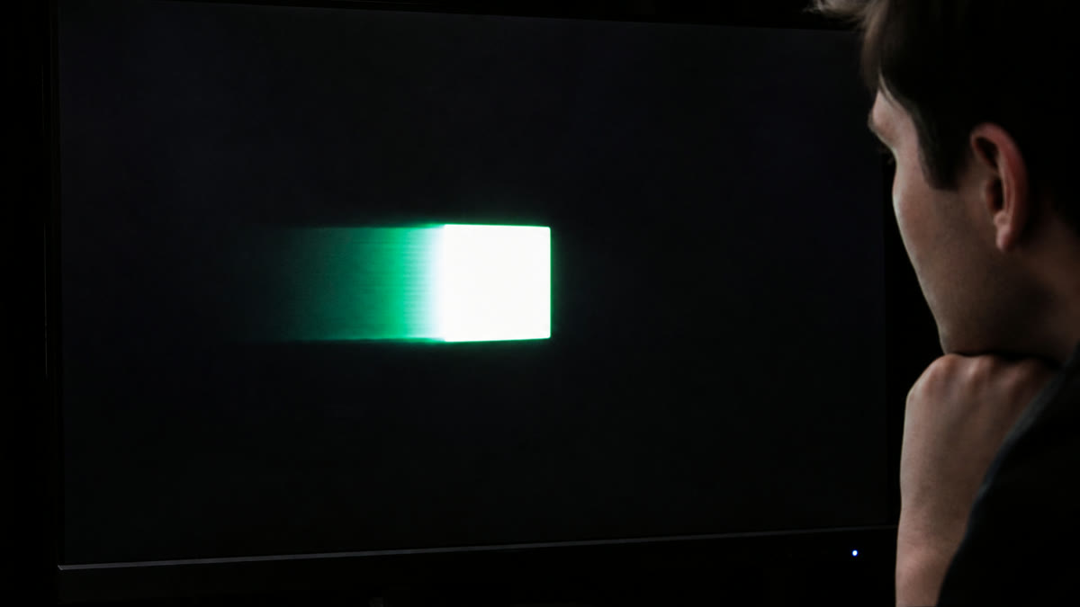 A gaming monitor showing a moving block with a bright inverse-ghosting halo around the leading edge.