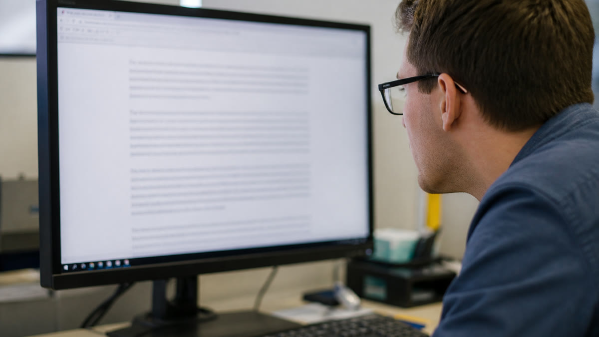 A desktop monitor showing small body text that looks soft and blurry instead of crisp while someone tries to read.
